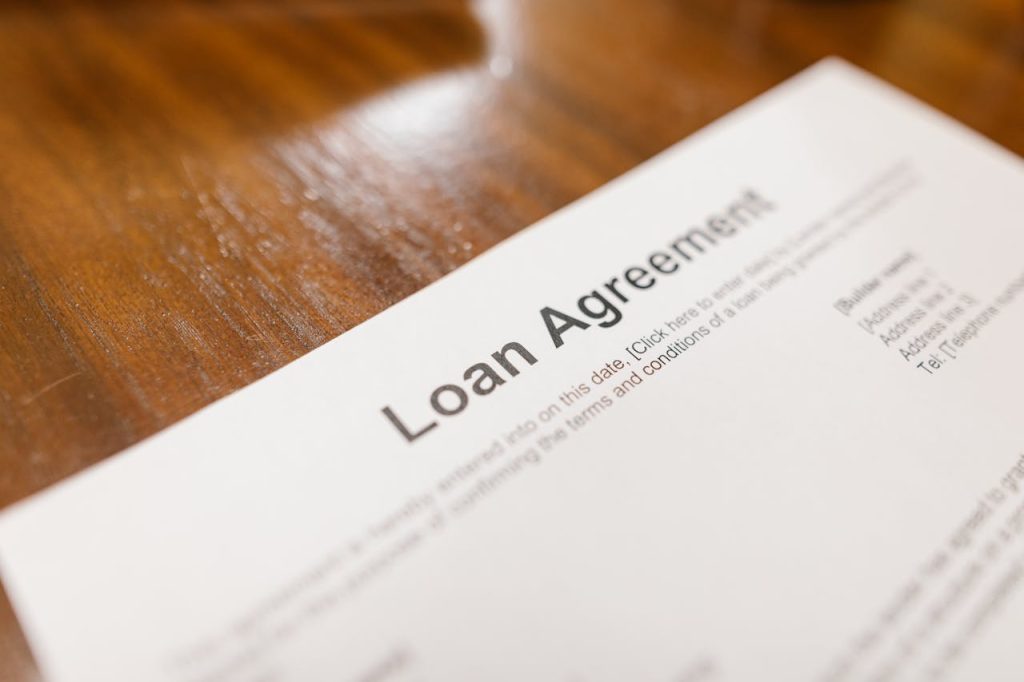 close-up-photo-of-an-agreement-on-a-paper-7841821 Detailed loan agreement document close-up on a wooden table representing legal and financial concepts.