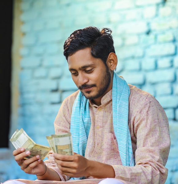 Happy Indian farmer counting money at home.